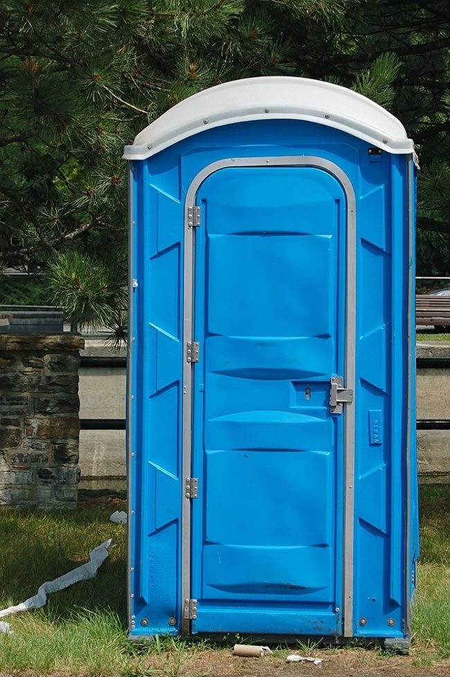 Construction crew taking a break beside portable restroom units on site