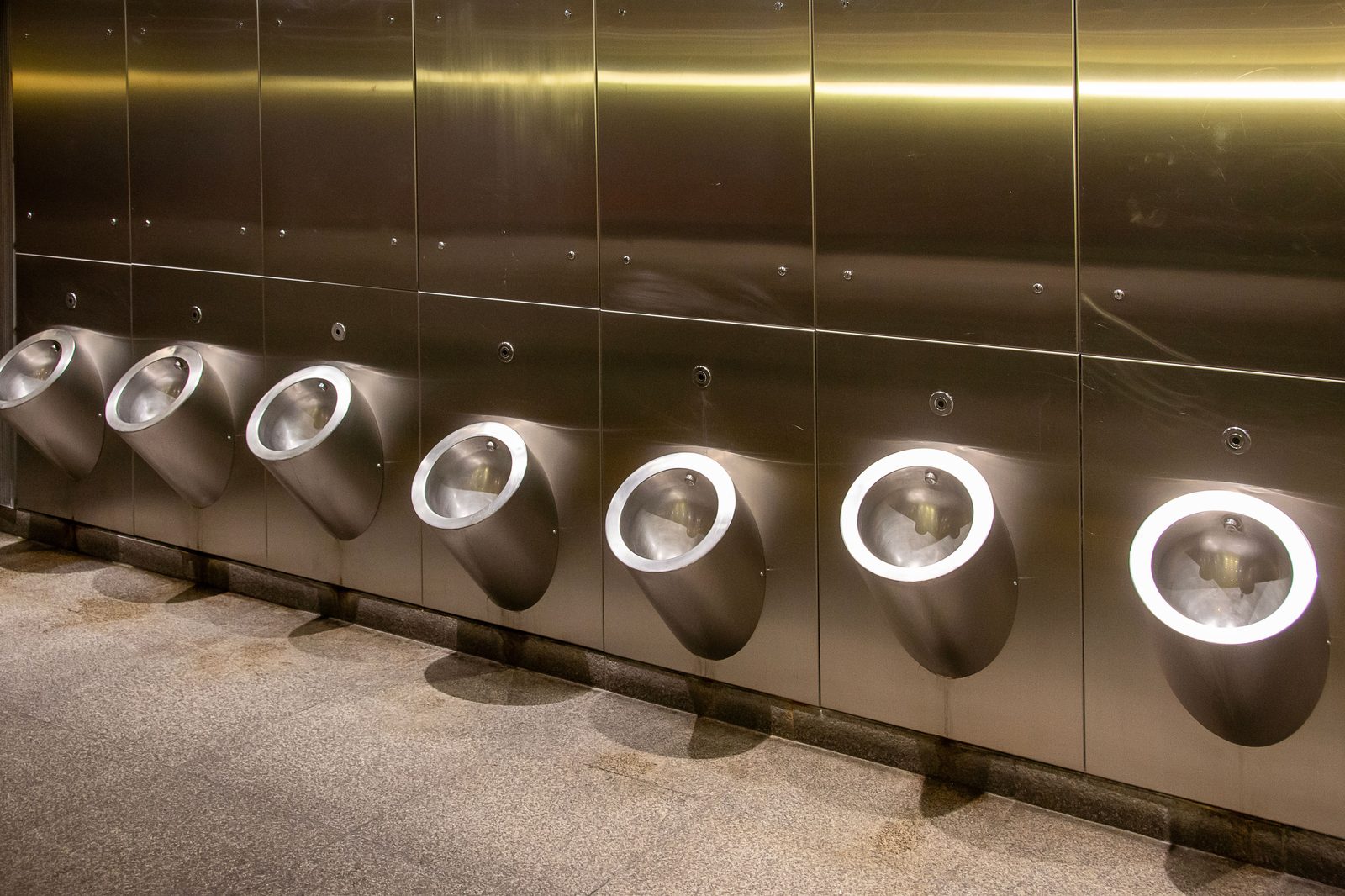 Row of modern illuminated urinals in a clean restroom facility