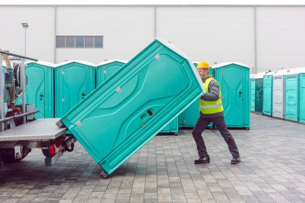 Crew loading teal portable restroom units onto a delivery trailer